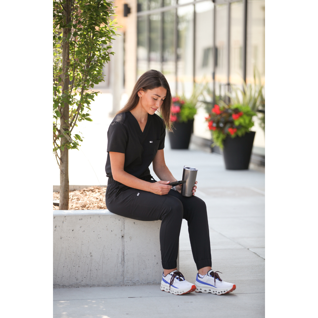 Woman Texting in Real Black Women&#39;s Tuckable One-Pocket Scrub Top and Perfect Joggers