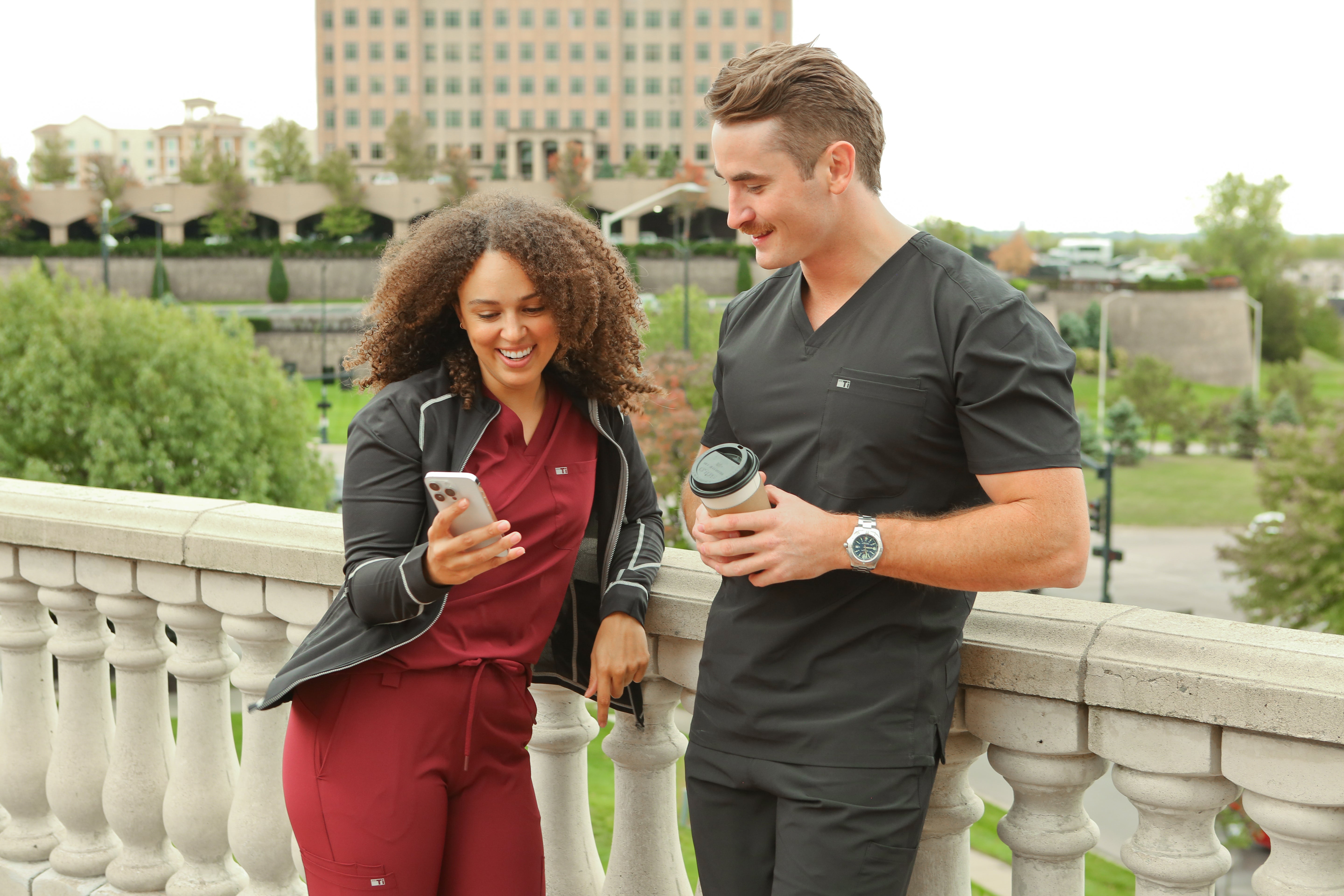 Man and Woman Looking at Phone in Burgundy and Black Scrubs