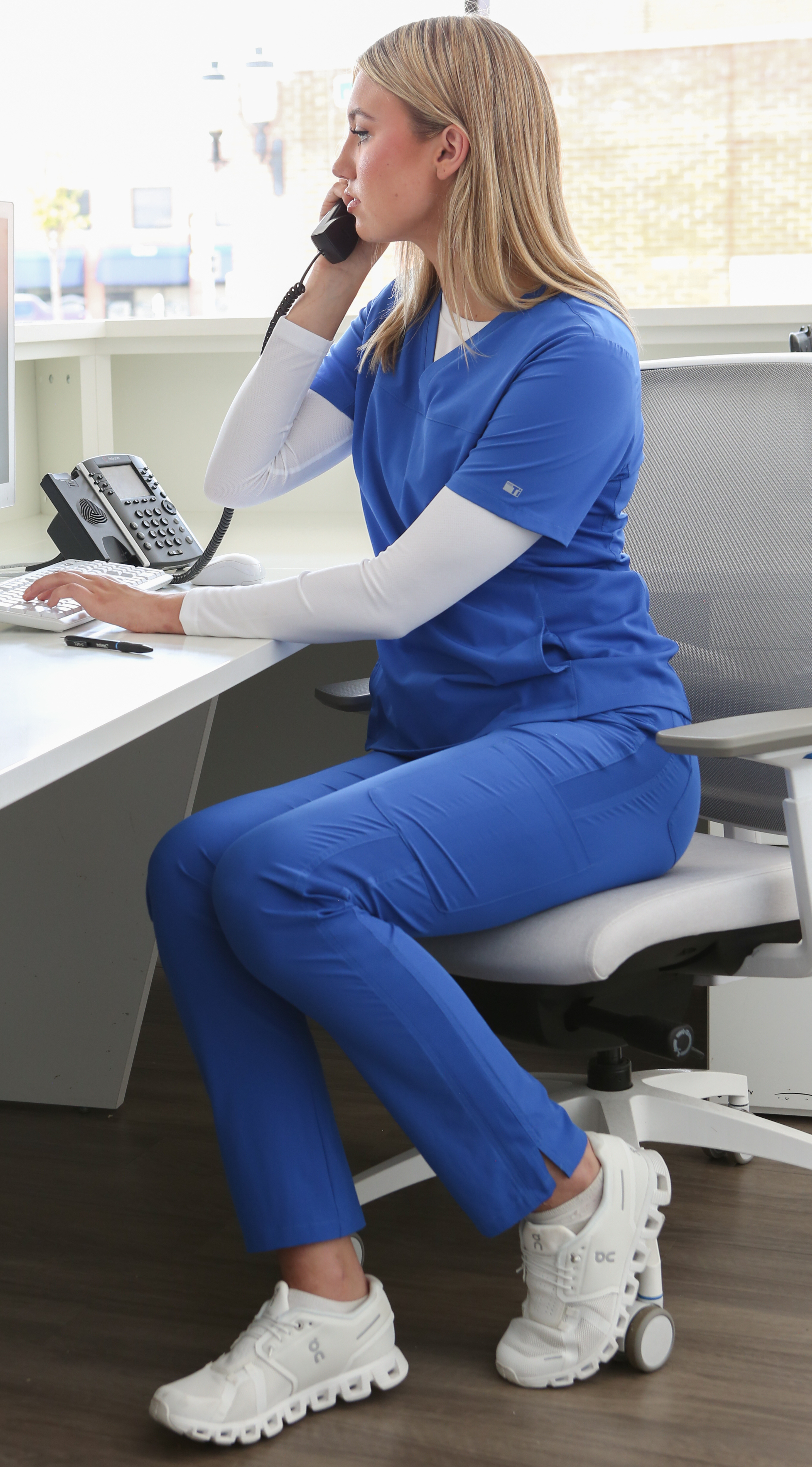 Woman Working at Desk in Royal Blue 9-Pocket Scrub Pants and Stash-Pocket Scrub Top