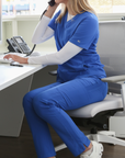 Woman Working at Desk in Royal Blue 9-Pocket Scrub Pants and Stash-Pocket Scrub Top