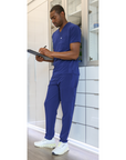 Man Standing with Clipboard Medical Supply Room in Navy 9-Pocket Scrub Pants and Double-Pocket Scrub Top