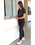 Woman Writing Patient Paperwork in Black Perfect Scrub Joggers and One-Pocket Top
